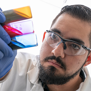 Researcher looks at yellow, red, and blue colored liquids in vials