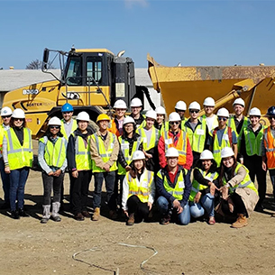 A group of ASCE members pose in front of a large truck on a job site